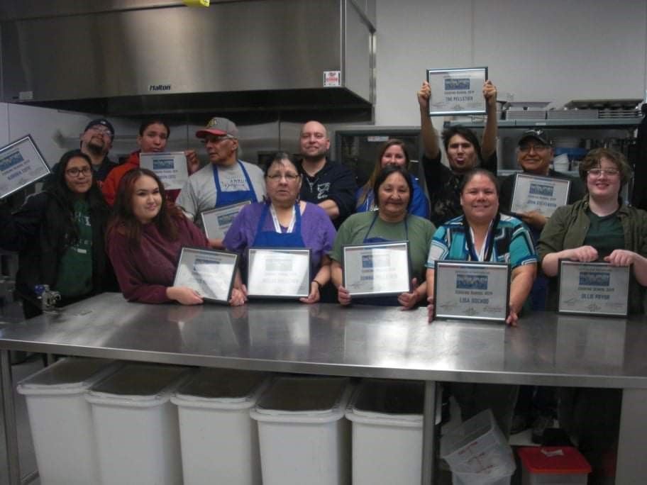 Staff and community members celebrating cooking course graduation in 2019.
